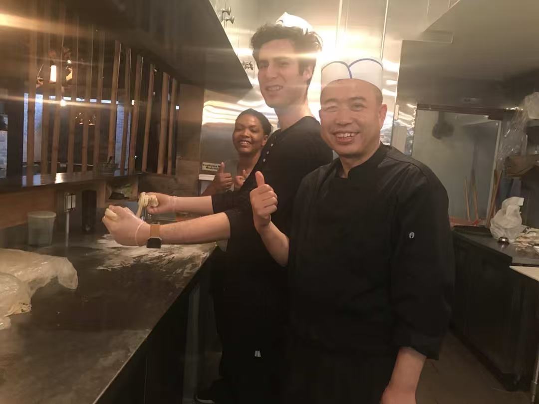 Master chef with two international apprentices in the open kitchen